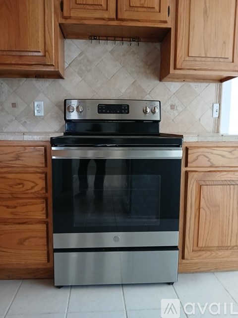 A modern stove with a glass top is installed in a kitchen with wooden cabinets.