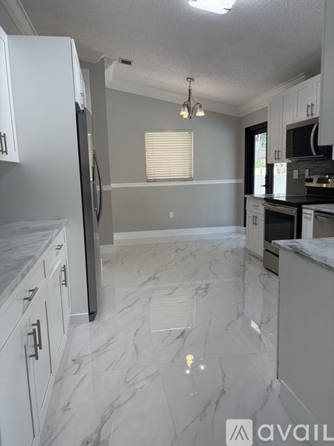 A kitchen with white cabinets and marble flooring.