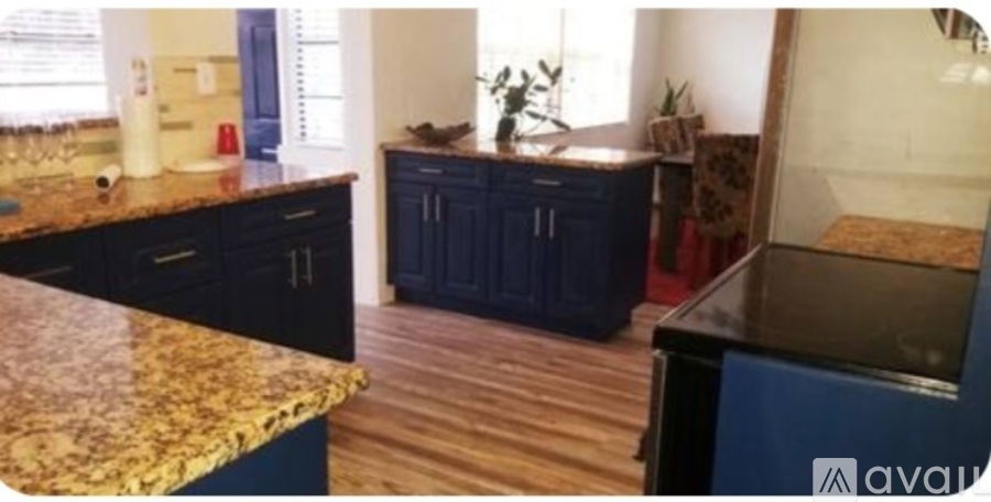 A kitchen with dark blue cabinets and a marble countertop.