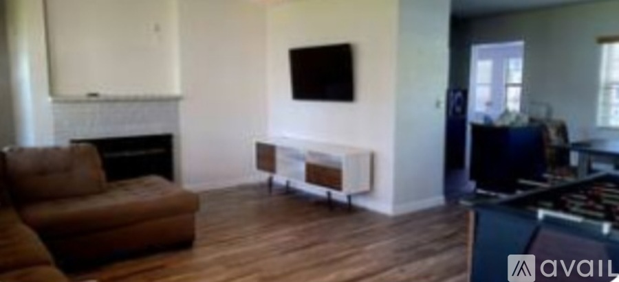 A living room with a brown couch and a white fireplace.