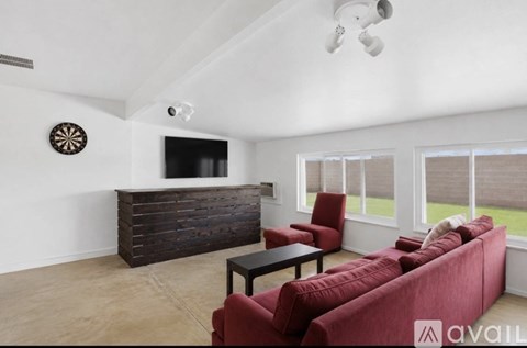 A living room with a red couch and a dart board on the wall.