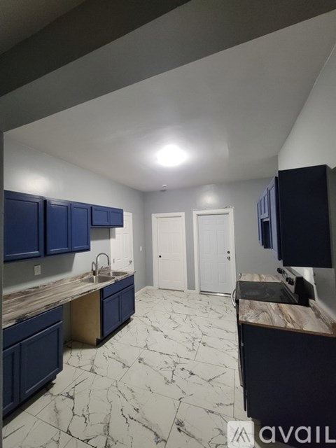 A kitchen with blue cabinets and marble flooring.