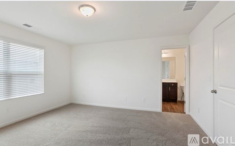 A room with a carpeted floor and a door leading to another room.