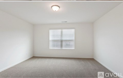 A room with a carpeted floor and a window with blinds.