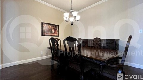 A living room with a black couch and a chandelier.