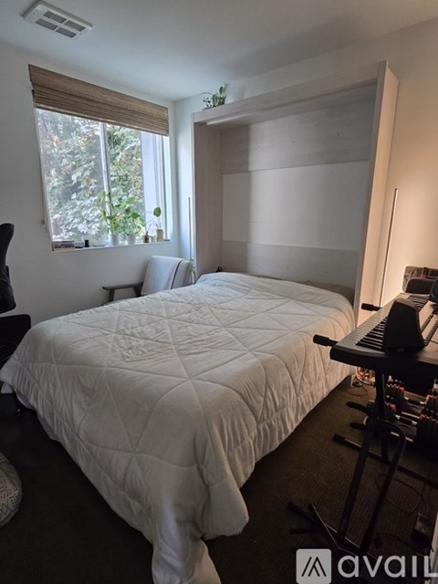 A bedroom with a large bed and a window with blinds.