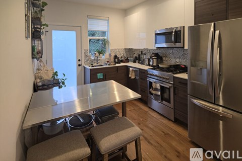 A kitchen with a stainless steel refrigerator and a countertop with a plant on it.