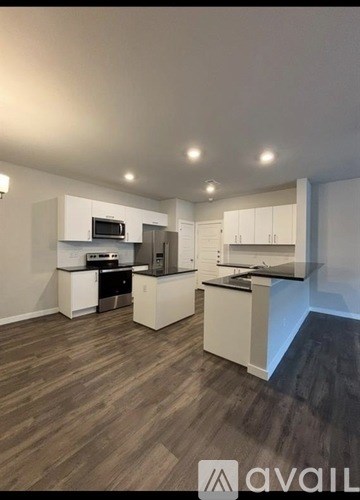 A modern kitchen with white cabinets and a wooden floor.