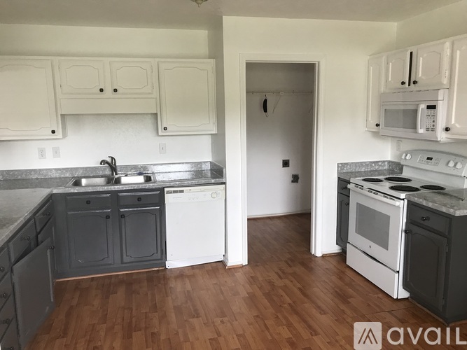 A kitchen with white cabinets and a wooden floor.
