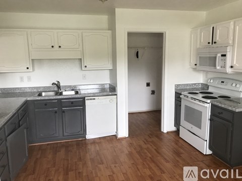 A kitchen with white cabinets and a wooden floor.