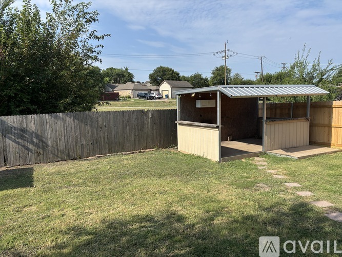 A backyard with a wooden fence and a small building.