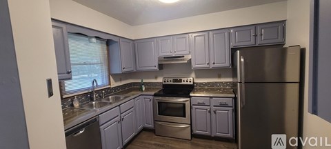 A kitchen with a refrigerator, oven, and sink.