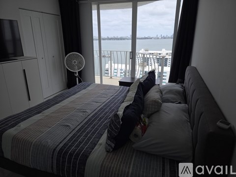 A bedroom with a large bed and a balcony overlooking a body of water.