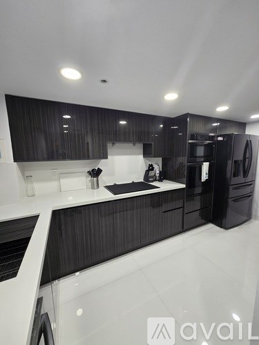 A modern kitchen with black cabinets and white countertops.