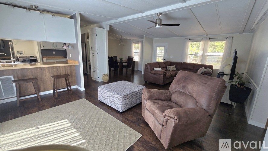 A living room with a brown couch and a white ottoman.