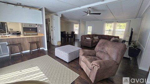 A living room with a brown couch and a white ottoman.