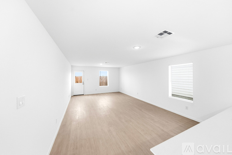A spacious room with wooden flooring and white walls.