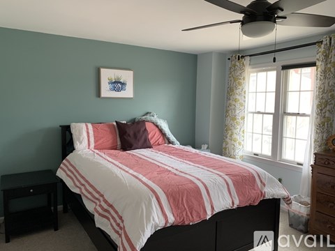 A bedroom with a bed, nightstand, and window.