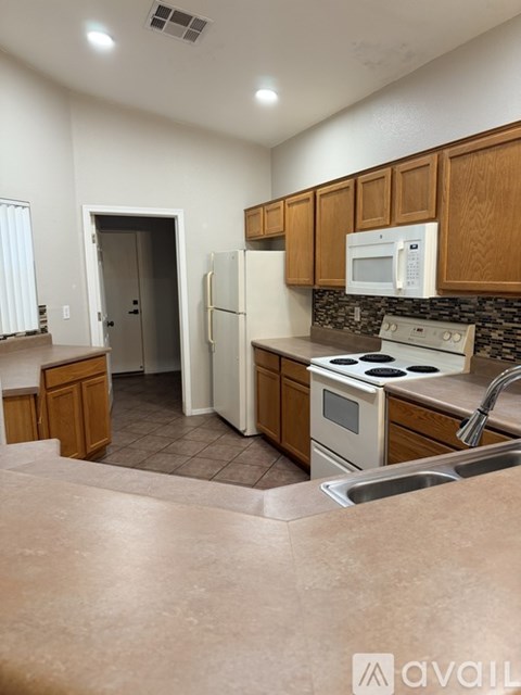 A kitchen with brown cabinets and a white fridge.