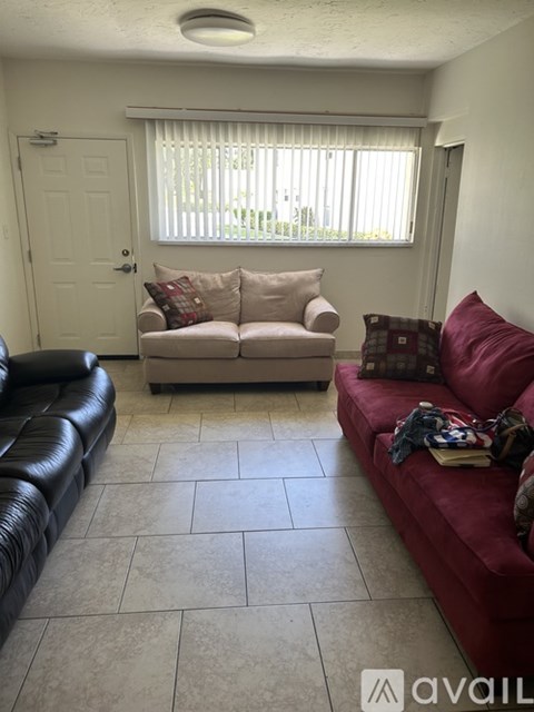 A living room with a red couch and a black leather couch.