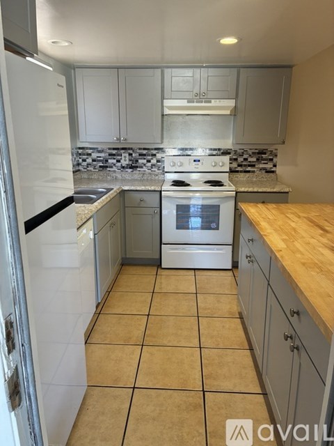 A kitchen with a white fridge, a white stove, and a wooden counter.