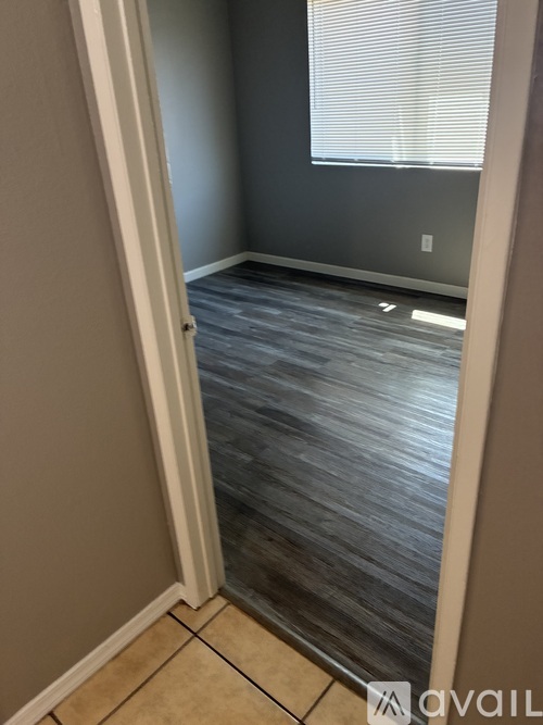 A room with a wooden floor and a window with blinds.