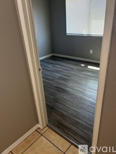 A room with a wooden floor and a window with blinds.