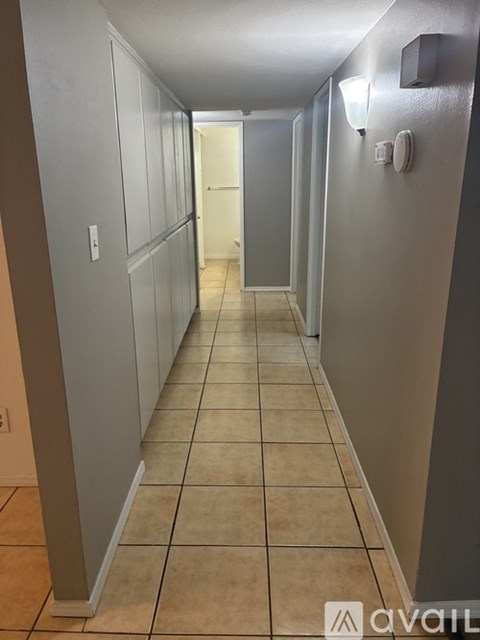 A long hallway with tiled floors and white walls.