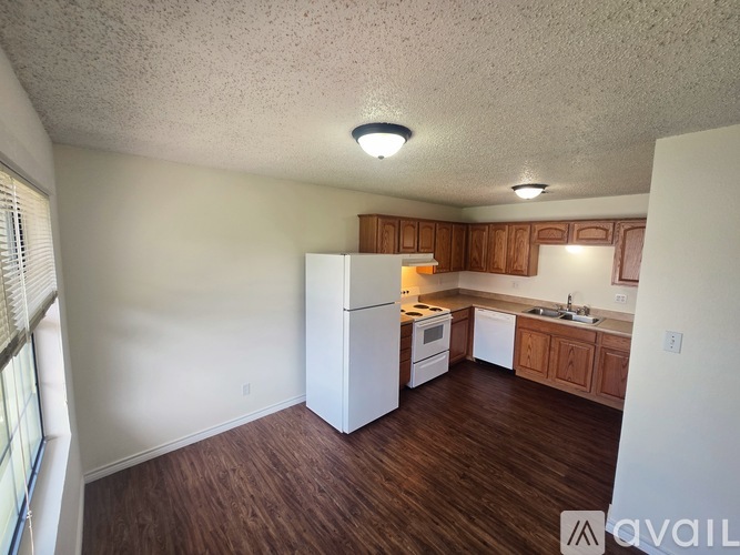 A kitchen with white appliances and wooden cabinets.