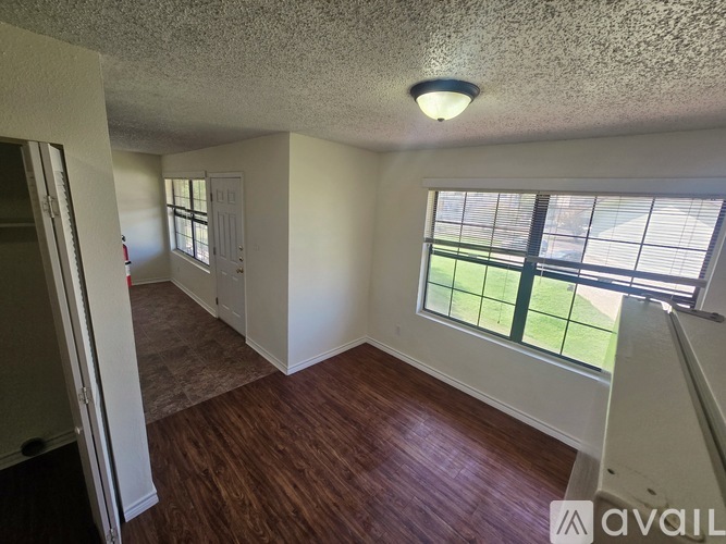 A room with a window overlooking a green field.