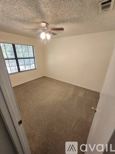 A room with a carpeted floor and a ceiling fan.