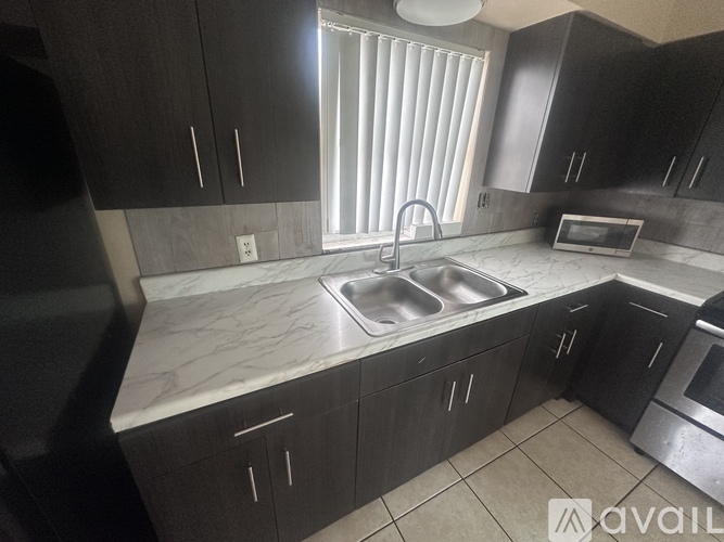 A kitchen with dark brown cabinets and a marble countertop.