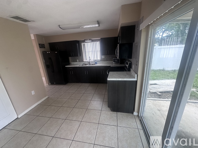 A kitchen with black cabinets and a white fridge is available.