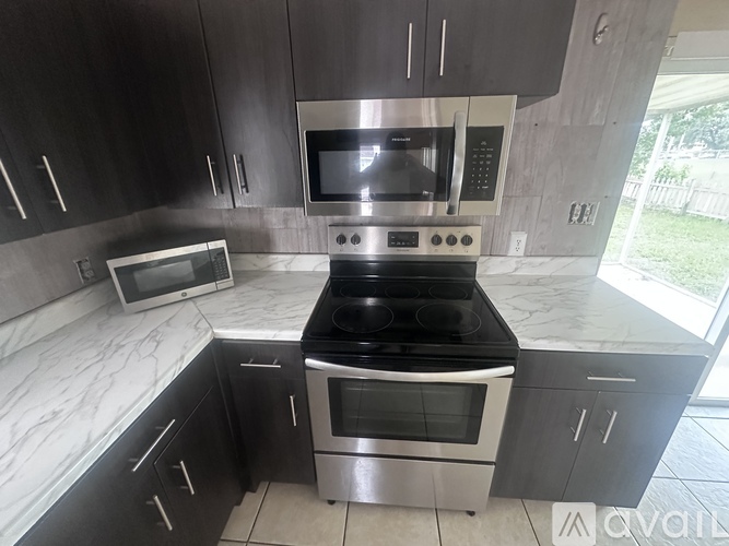A kitchen with black cabinets and a stainless steel oven.
