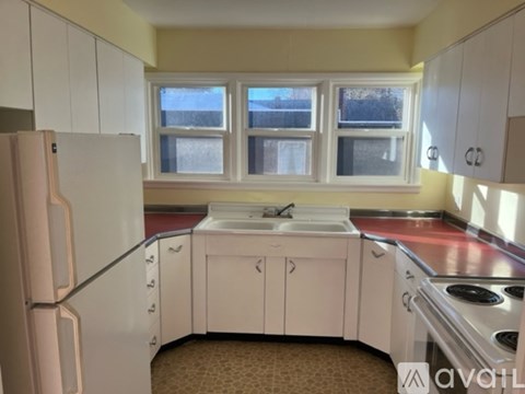 A kitchen with white cabinets and a pink fridge.