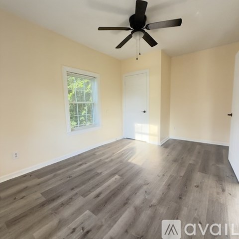 A room with a ceiling fan and wooden flooring.