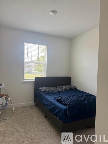 A bedroom with a bed, pillows, and a fan.