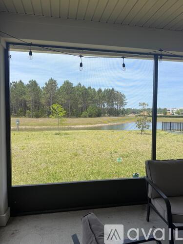 A patio with a chair and a view of a field and trees.