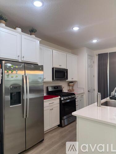 A kitchen with a stainless steel refrigerator and white cabinets.