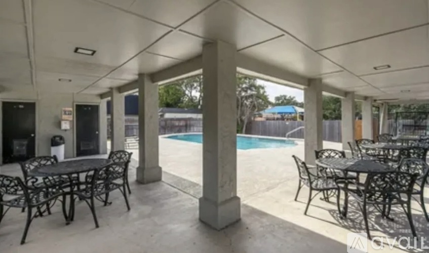 A patio with tables and chairs and a pool in the background.