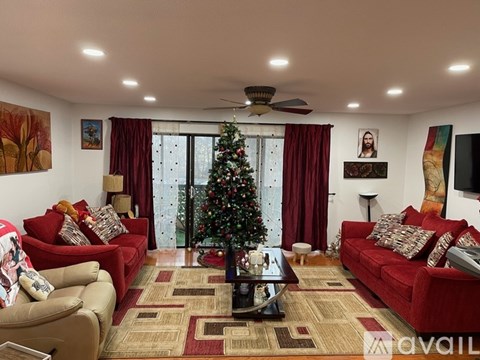 A living room with a Christmas tree and a fan.