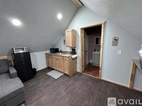 A kitchen area with wooden cabinets and a black fridge.