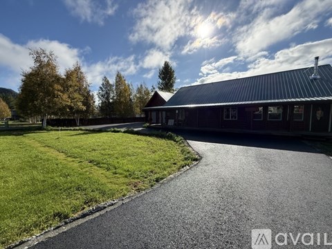 A building with a dark roof and a driveway leading to it.