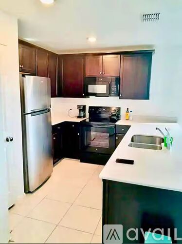 A kitchen with a refrigerator, microwave, oven, and sink.