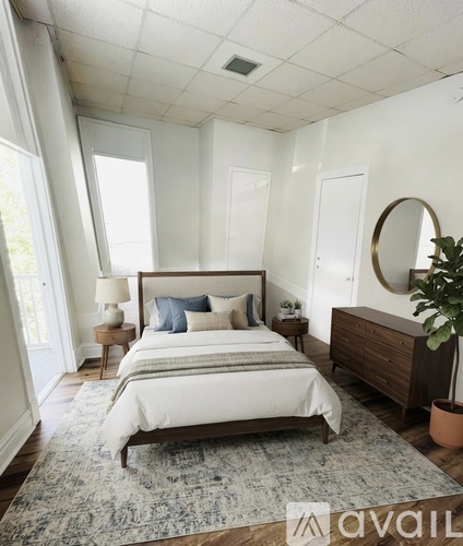 A bedroom with a large bed, a side table with a lamp, and a dresser with a mirror.