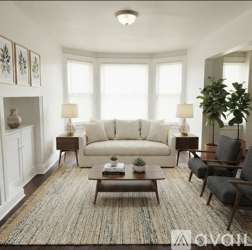 A living room with a white sofa, a wooden coffee table, and a large rug.