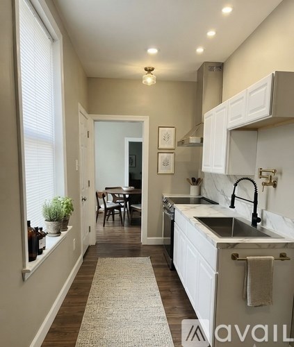 A kitchen with white cabinets and a marble countertop.