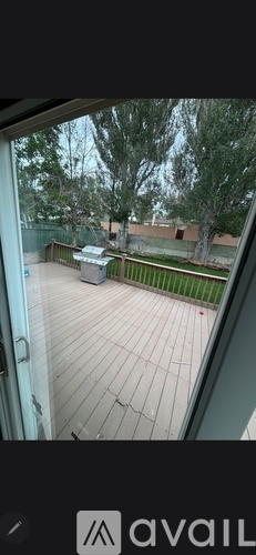 A view from a window looking out to a deck and trees.