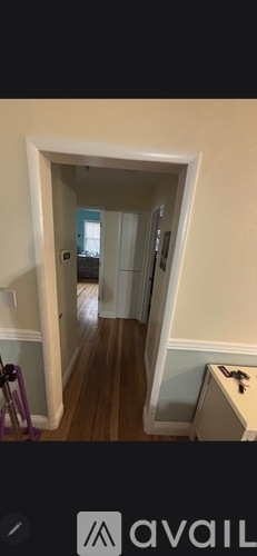 A hallway with wooden floors and white walls.
