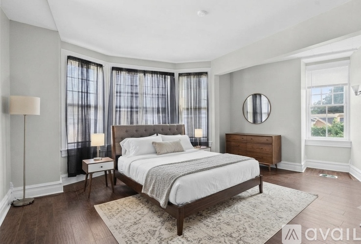 A bedroom with a large bed, a nightstand, and a lamp.